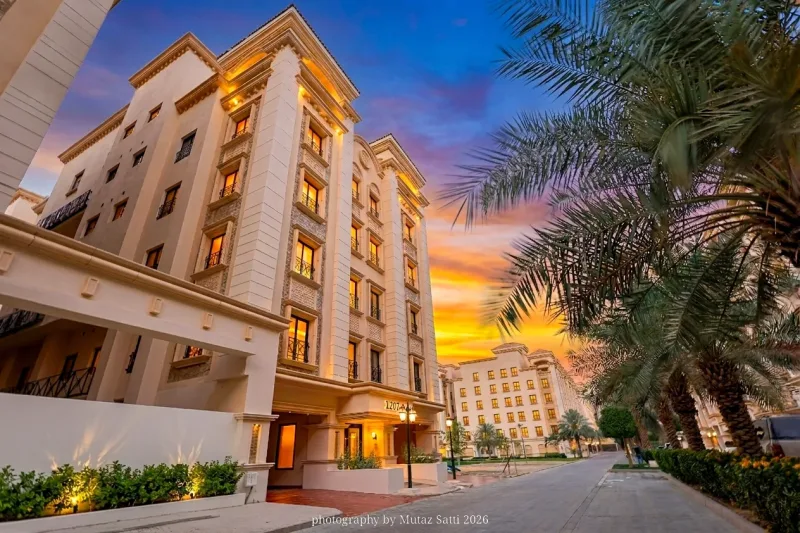 واجهة عمارة سكنية كلاسيكية عند الغروب مع إضاءة خارجية ونخيل — تصوير عقاري في جدة بعدسة معتز ساتي