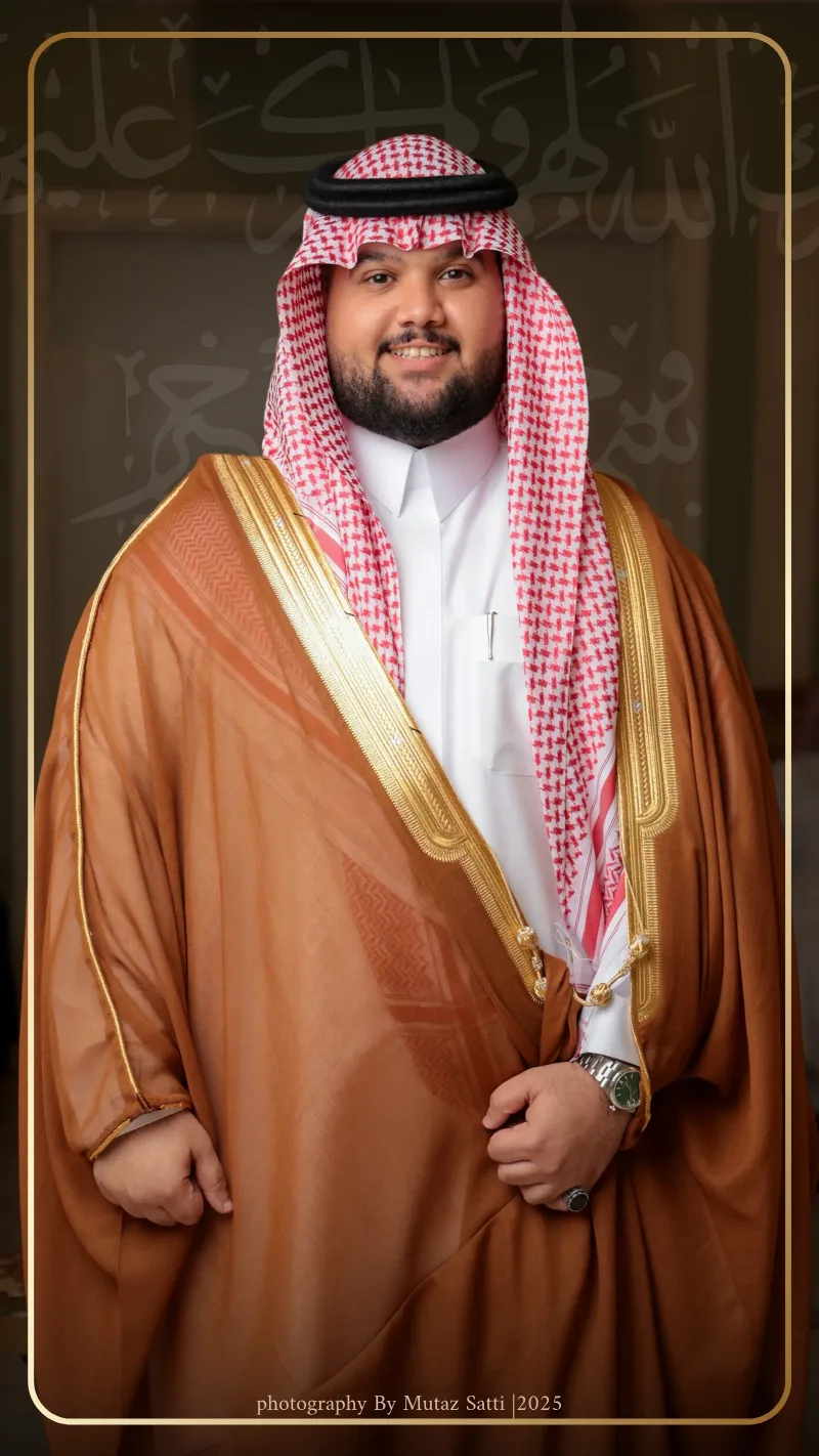 العريس بالبشت النحاسي وخلفه لوحة خطّ عربي — تصوير زواجات في جدة بعدسة معتز ساتي