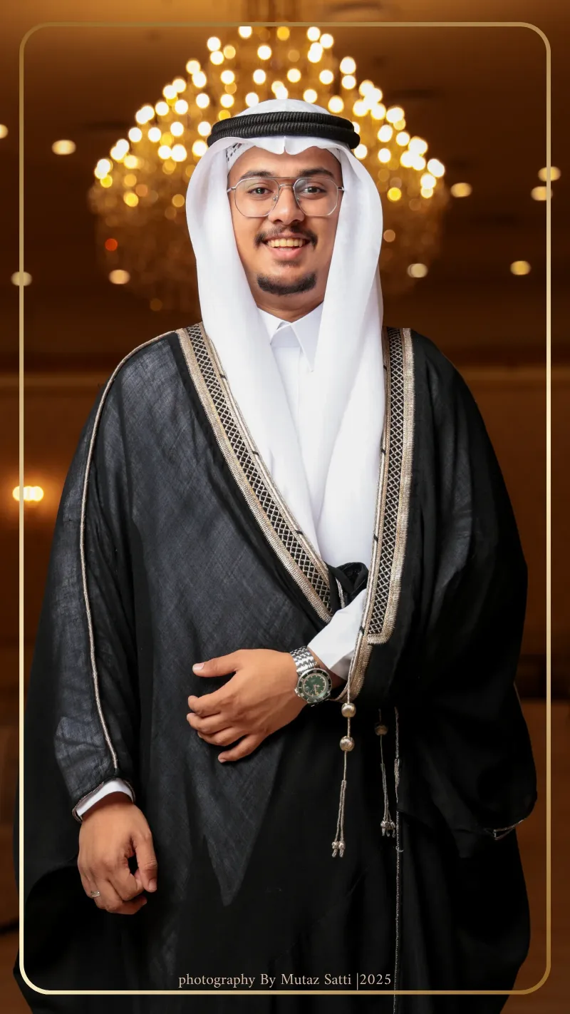 العريس جالسًا يتلقّى التهاني تحت إضاءة القاعة — تصوير زواجات في جدة بعدسة معتز ساتي
